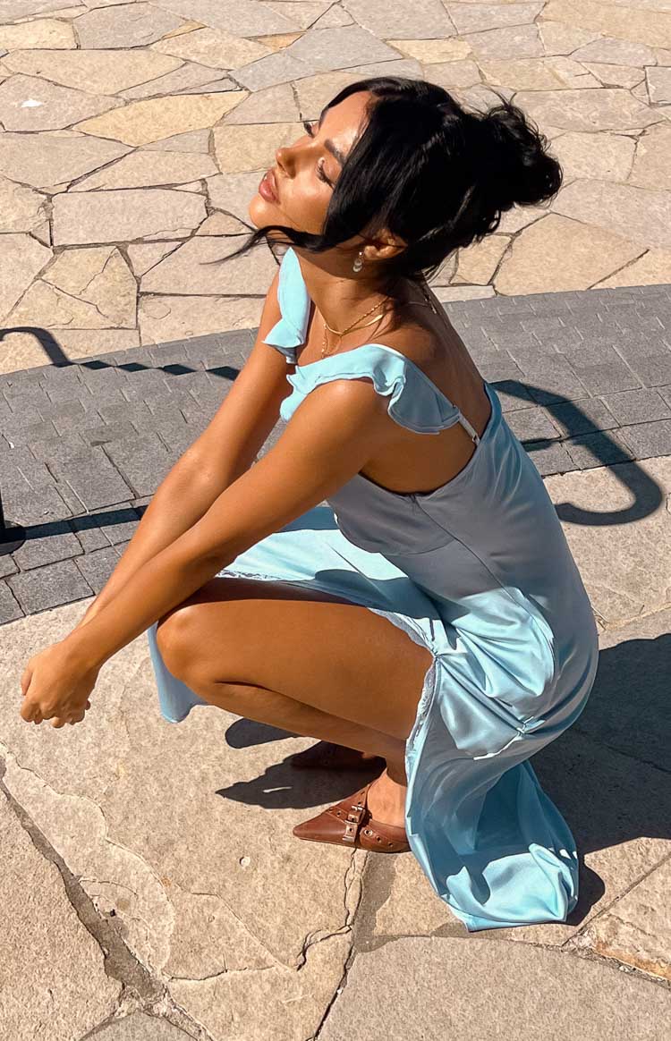 Side view of a light blue satin maxi dress with ruffled shoulder straps, adjustable spaghetti straps, low scoop back, and side lace trim