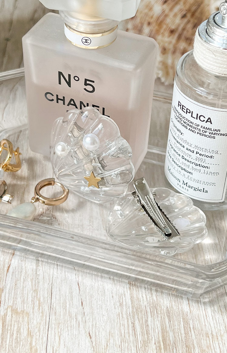 Clear shell hair clip with two white pearls and a gold star, showing the silver metal alligator clip mechanism