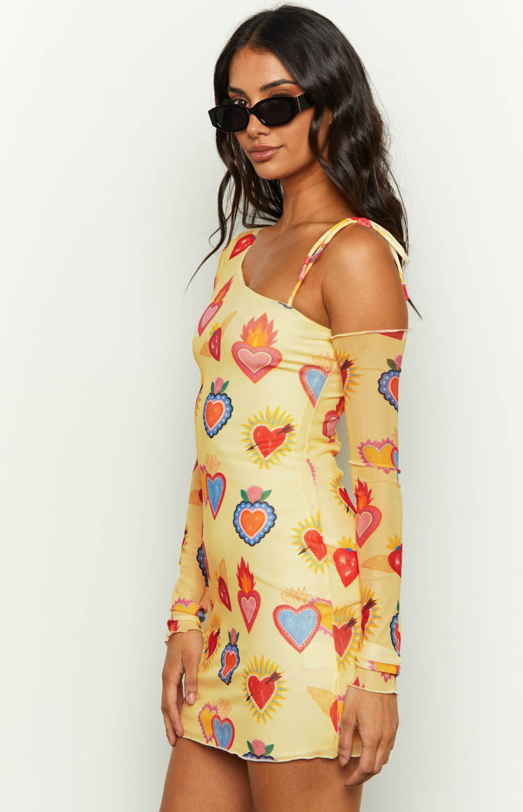 Side view of yellow mesh mini dress with one-shoulder neckline, thin strap, and long mesh sleeve
