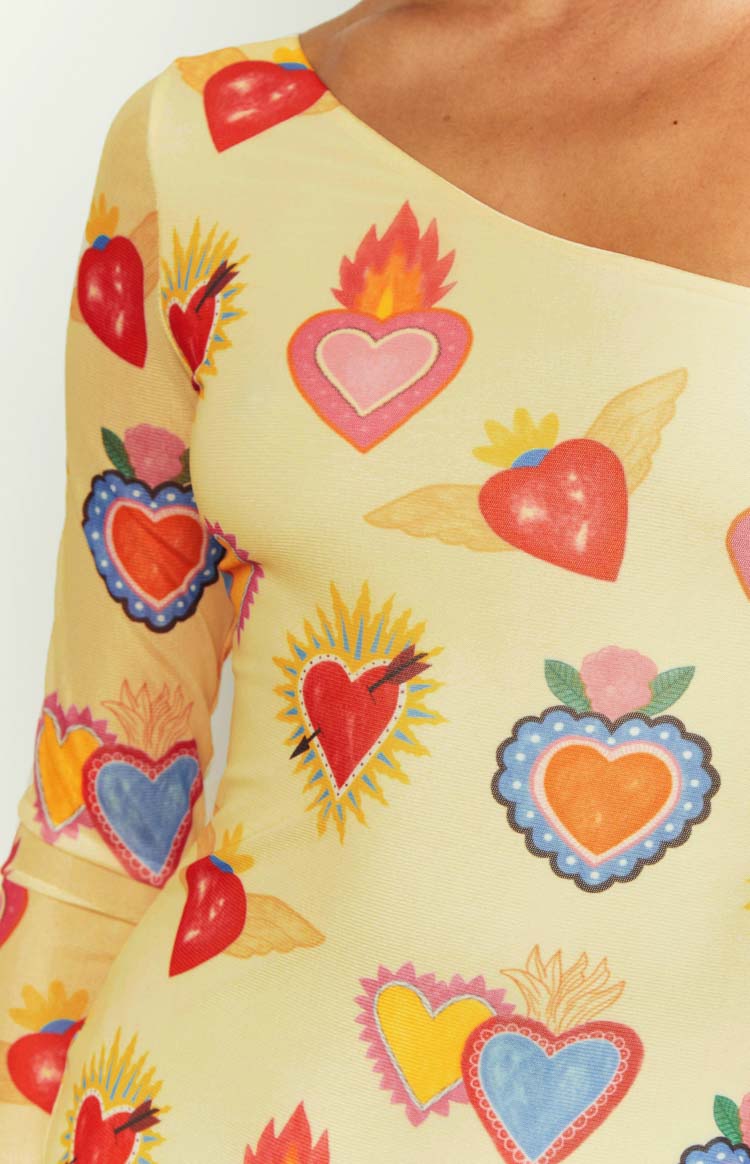 Close-up of the yellow mesh fabric with a detailed sacred heart print, showing the shoulder and long sleeve