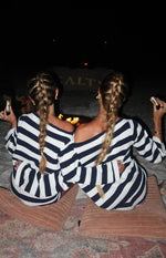 Rear view of a navy and white stripe knit sweater with an off-shoulder neckline and long sleeves