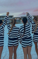 Back view of navy and white striped knit sweaters with long sleeves beach
