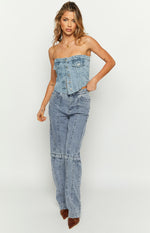 Front view of a mid-wash denim strapless button-front top with chest pockets and a curved hem