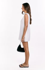 Side view of a white linen shift mini dress with a relaxed, straight fit and sleeveless design