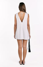 Rear view of a white linen shift mini dress with a deep V-neckline and tie detail at the back