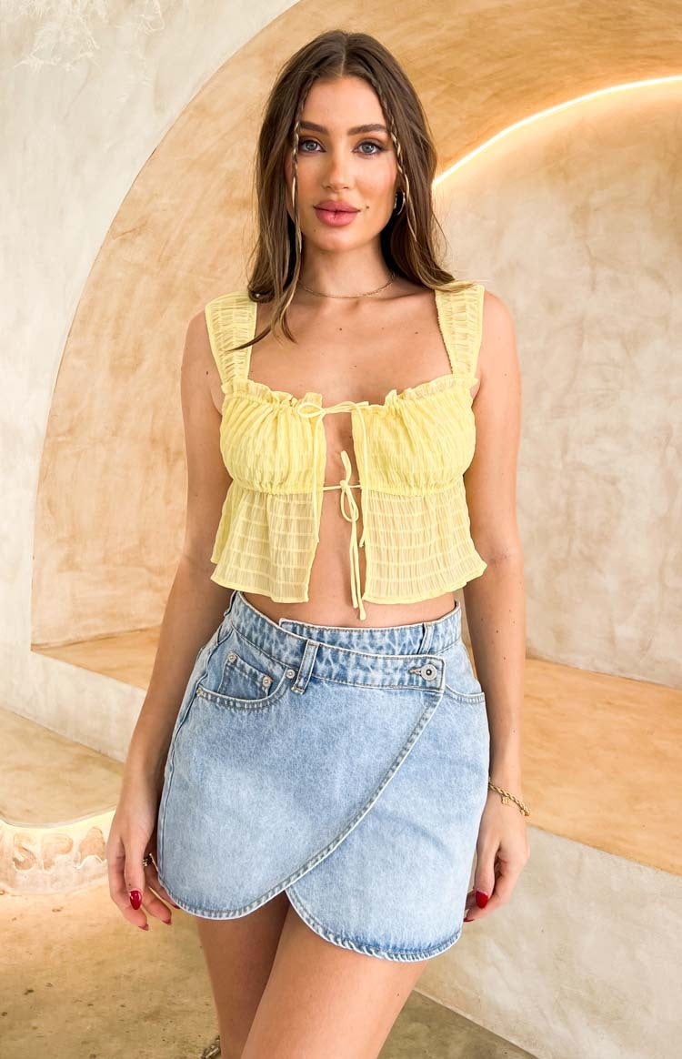 Light wash denim mini skirt with an asymmetrical wrap front and curved hem