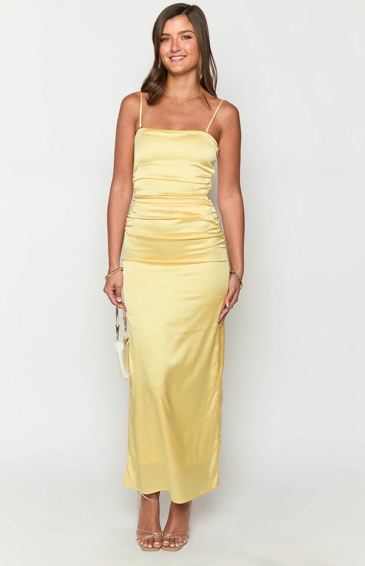 Front view of a yellow satin maxi dress with a square neckline, thin spaghetti straps, and ruched side detailing