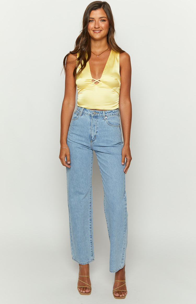 Criss-cross strap detail at the deep V-neckline of the yellow satin top