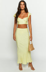 Full length view of a light yellow satin maxi skirt with a smooth, flowing drape
