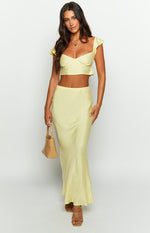Front view of a yellow satin maxi skirt with a fitted waist and flowing silhouette