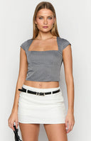 Girl looking away wearing black long sleeve top and white mini skort on street.