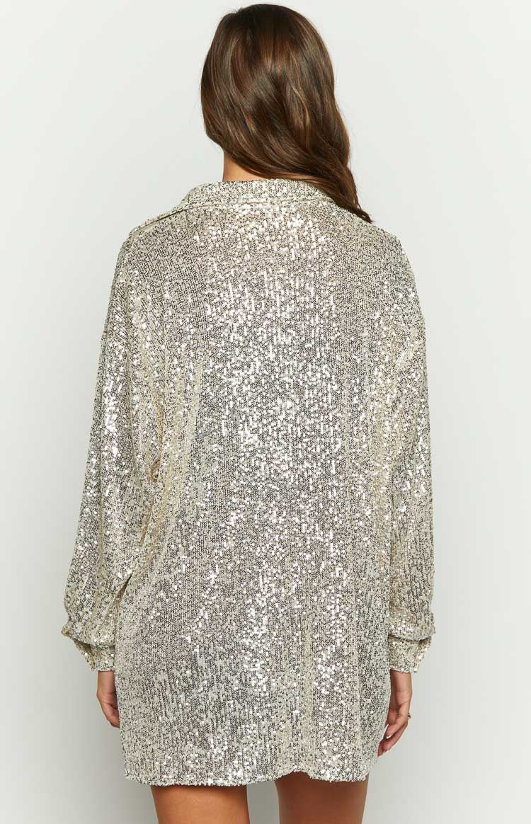 Close-up of the gold sequin fabric, collared neckline, and button-front detail of the long sleeve shirt