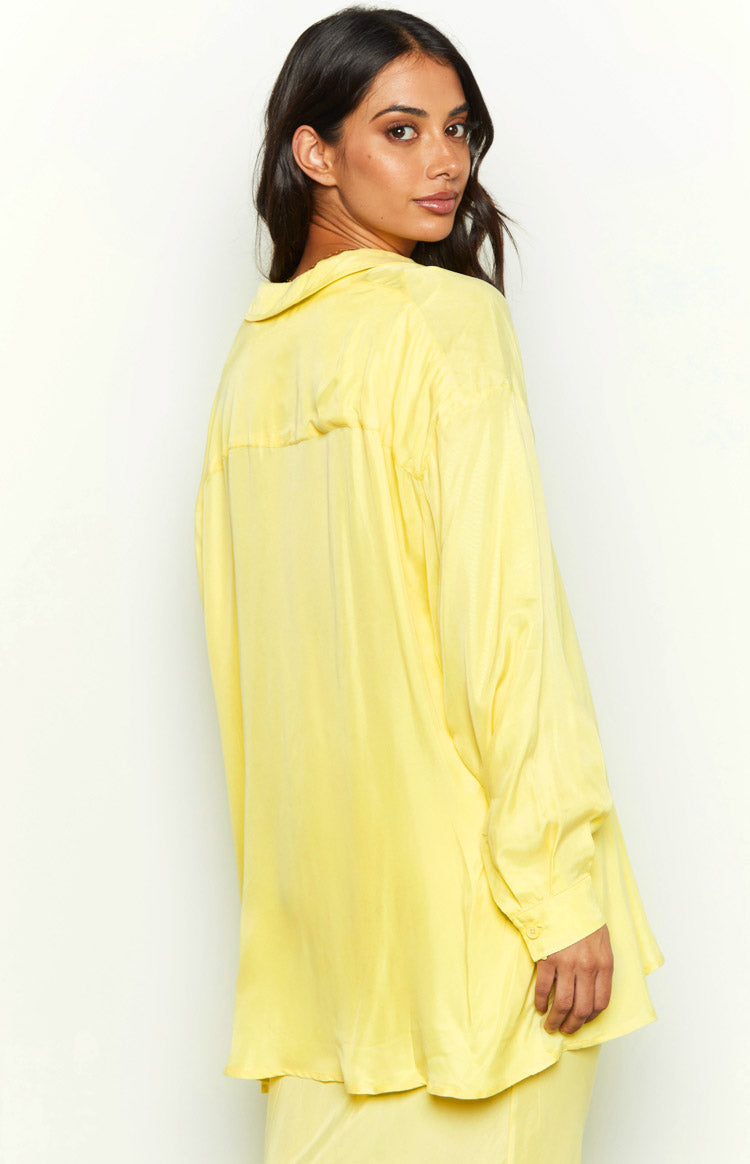 Front view of a yellow cupro button-up shirt with an open collar, long sleeves, and a relaxed, curved hem