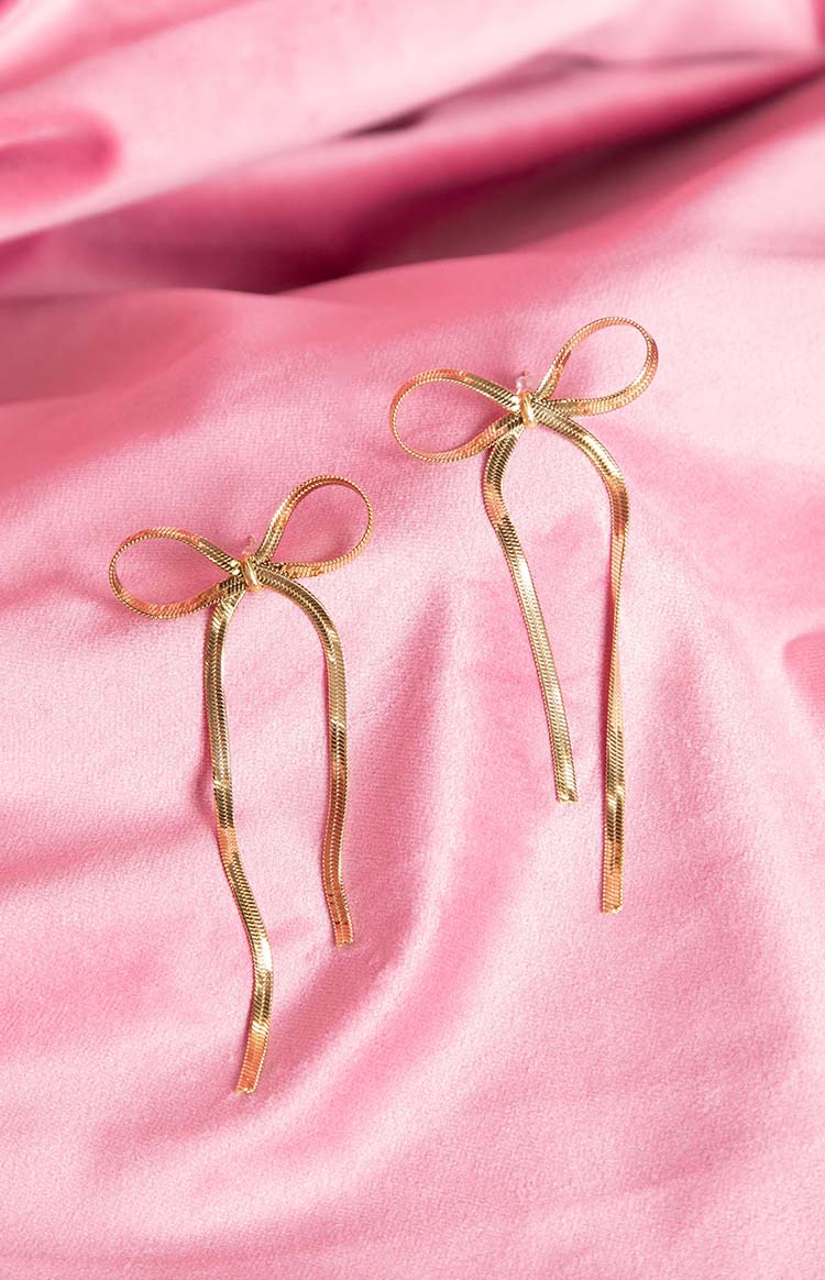 Gold bow earrings with a textured snake chain design forming the bow and long drops