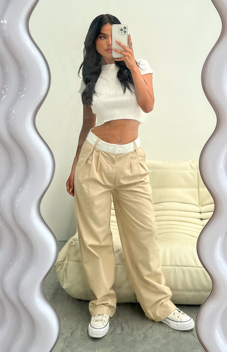 Full length view of tan wide-leg pants with a contrasting white waistband and front pleat details