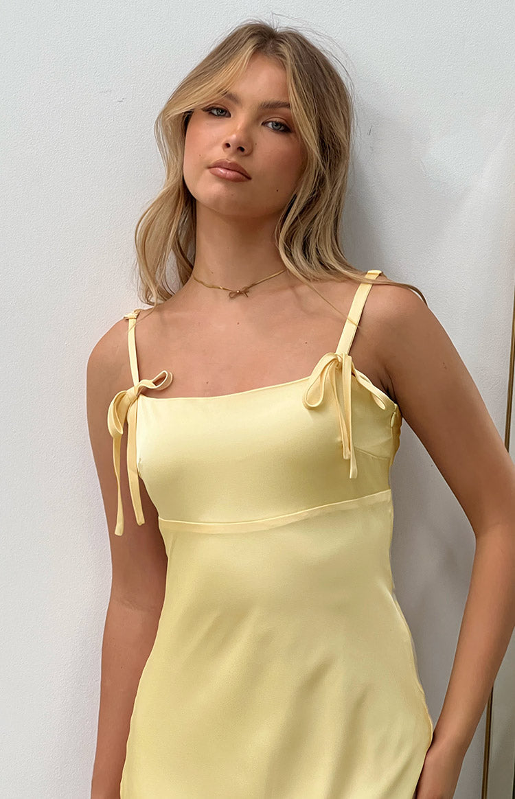 Detail shot of the square neckline and self-tie spaghetti straps on a yellow satin maxi dress