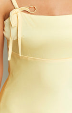 Close-up of the yellow satin tie-shoulder strap detail on the maxi dress