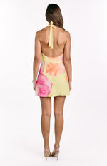Rear view of a yellow hibiscus floral print mini dress with a halter neck tie and low scoop back