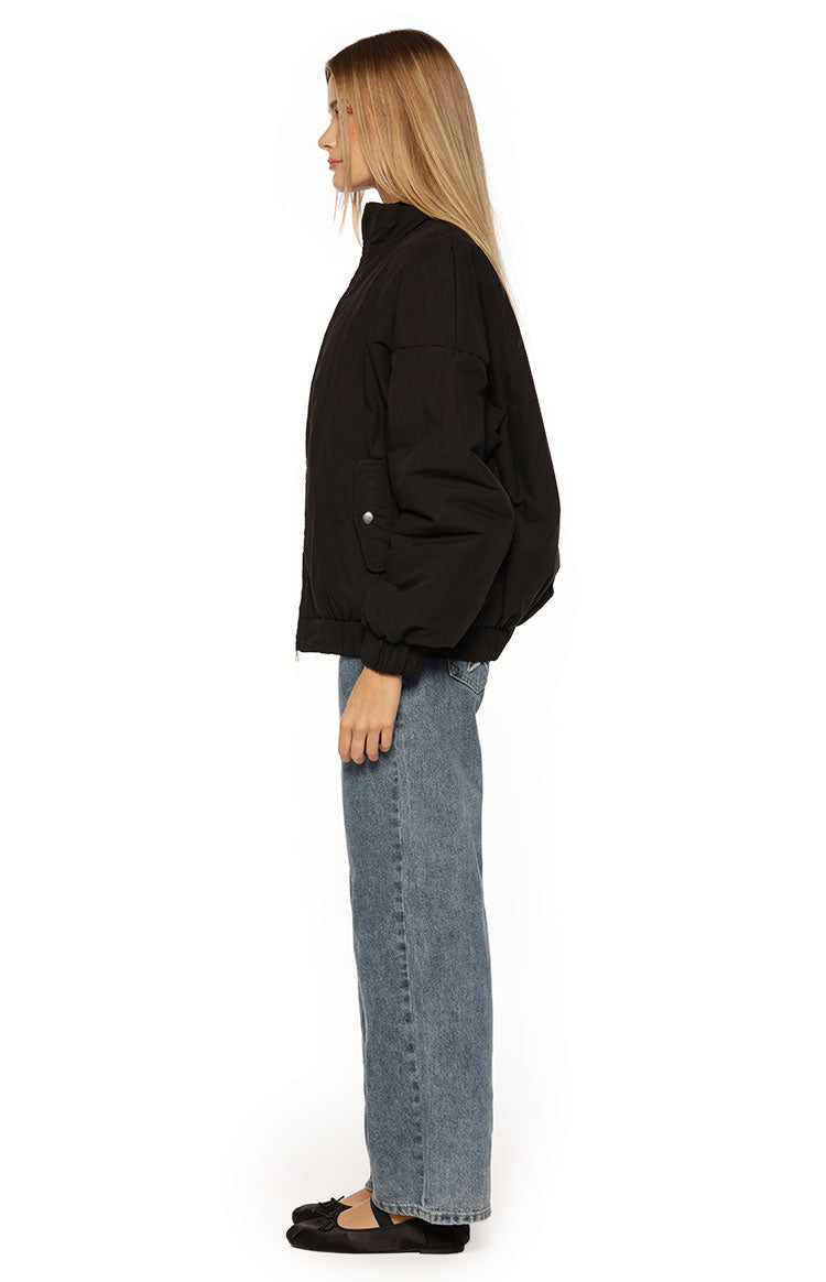 Side view of the black oversized puffer jacket with a high collar and elasticated hem