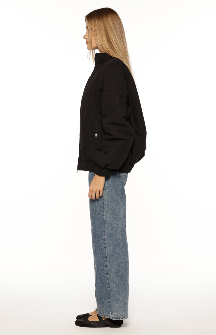 Side view of the black oversized puffer jacket with a high collar and elasticated hem