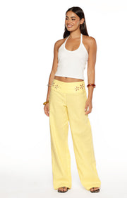 Yellow wide-leg pants with floral cutouts on the waistband and a relaxed fit