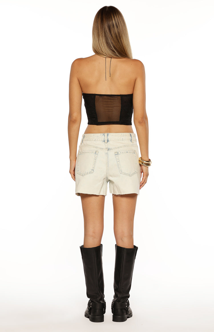 Rear view of light blue acid wash denim shorts with back pockets and a frayed hem