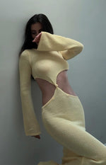 Side profile of a yellow knit maxi dress featuring large waist cutouts with a central knot and long bell sleeves