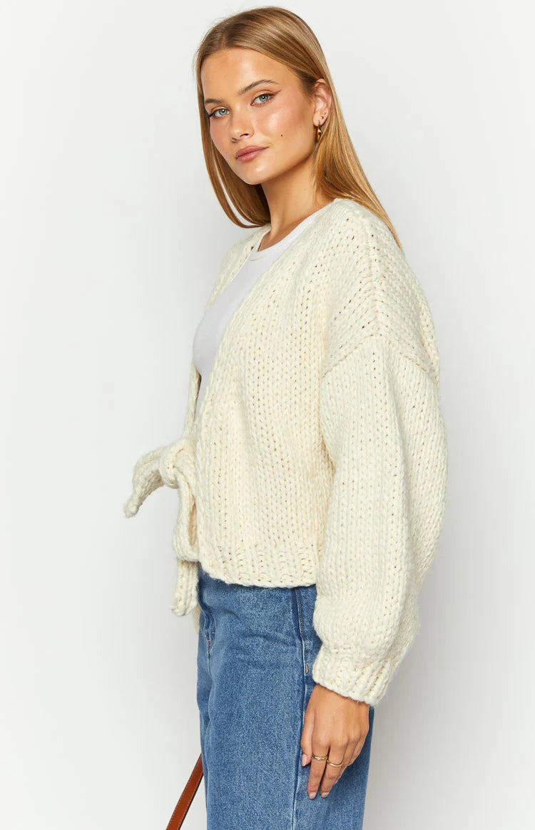 Cream chunky knit cardigan with a tie-up front and voluminous long sleeves, cropped length