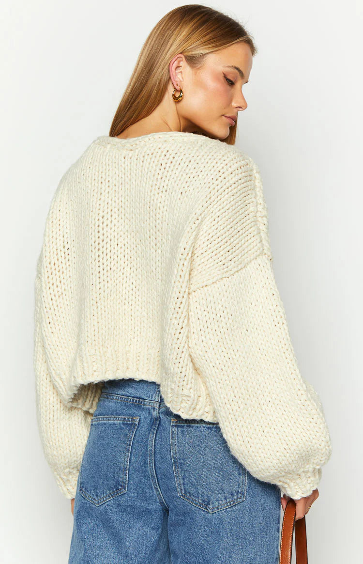 Close-up of a cream chunky knit cardigan with a tie-up front closure and wide ribbed cuffs