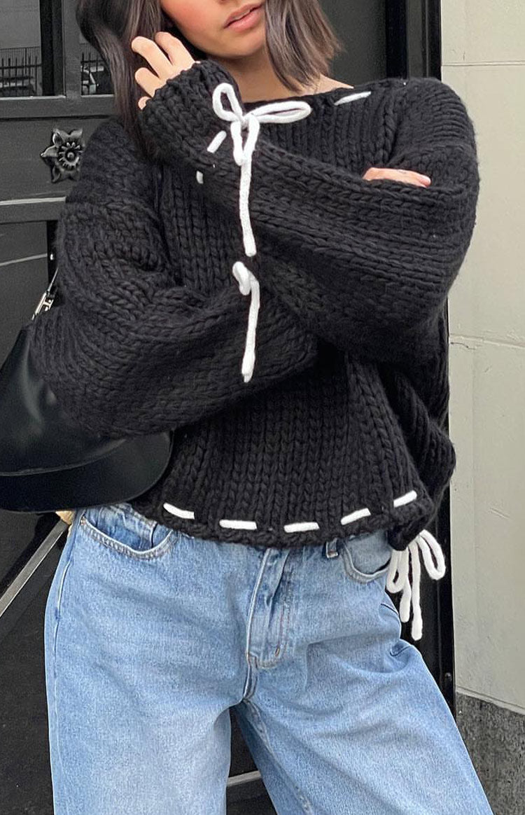 Black chunky knit sweater with white lacing detail on the round neckline, long sleeves, and hem