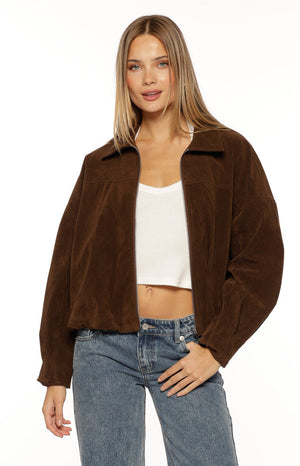 Our model wearing a cropped zip-front jacket in a dark brown corduroy fabric. This jacket has a wide pointed collar a relaxed fit through the shoulders and a gathered elasticized hemline.