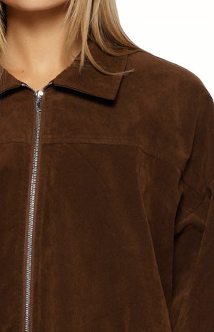 Close-up of the brown suedette bomber jacket showing the silver front zipper, pointed collar, and soft texture