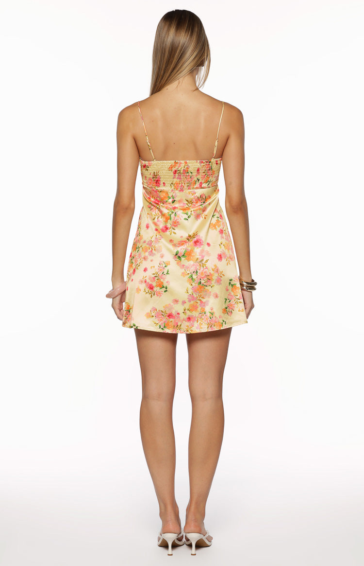 Rear view of a yellow floral mini dress with a smocked back and thin spaghetti straps
