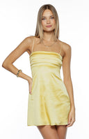 Our model is wearing a mini slip dress in a yellow satin fabric. This dress features a straight square neckline with several horizontal pleats detailing across the bust. It is suspended by very thin spaghetti straps. The smooth shimmering mini dress has a straight short silhouette.