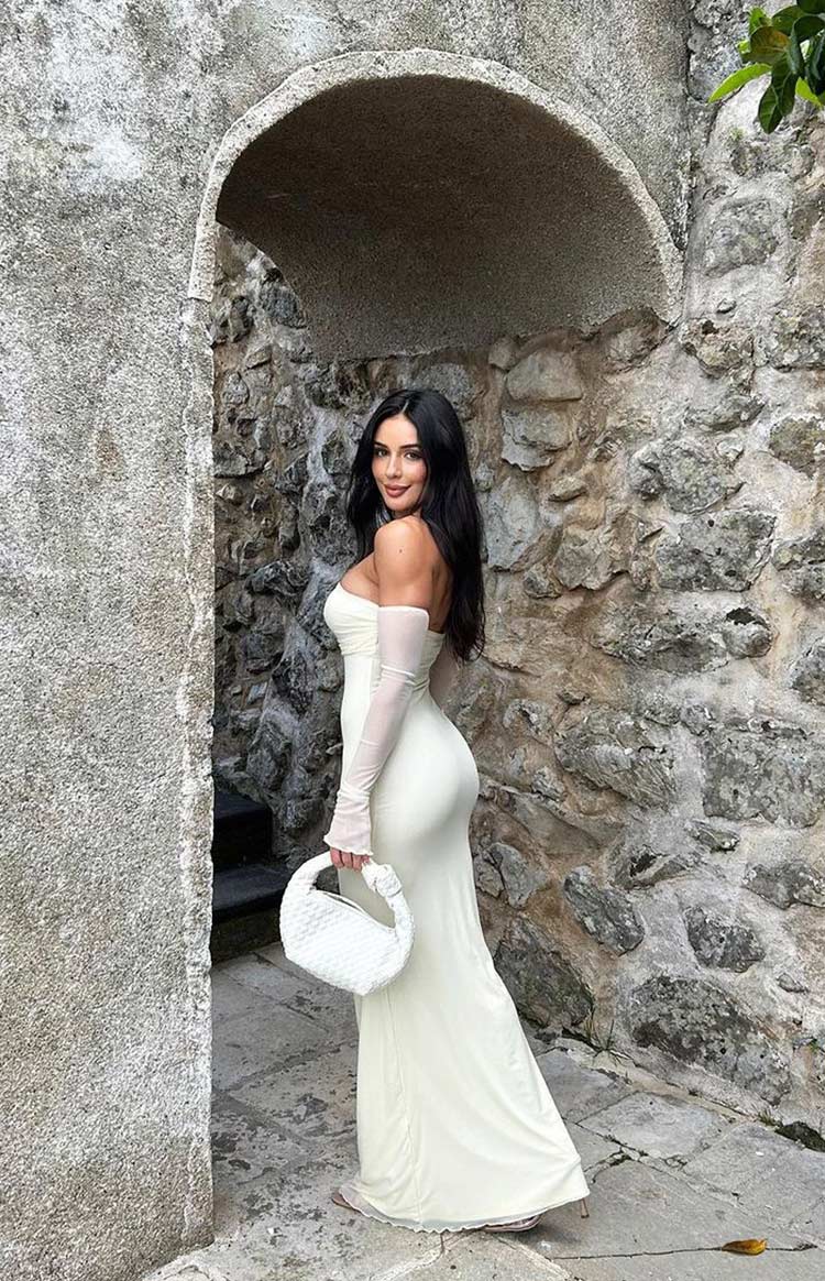 Close-up of the cream strapless maxi dress with ruched mesh bodice and sheer detached long sleeves with frilled cuffs