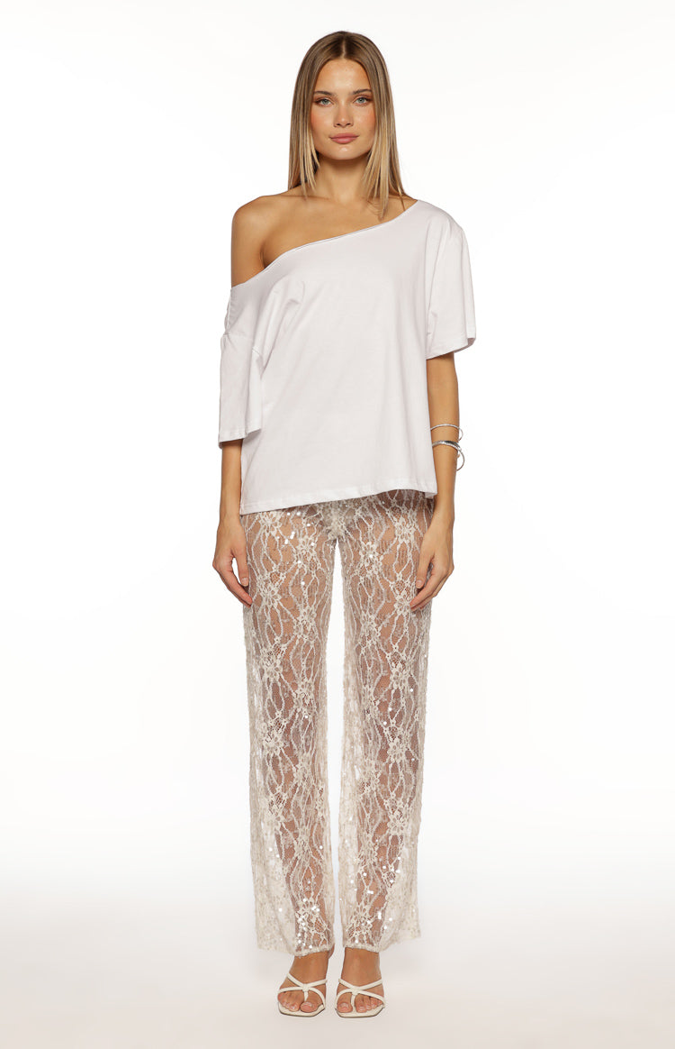 Full length view of white sheer lace wide-leg pants with an intricate pattern and scattered sequins
