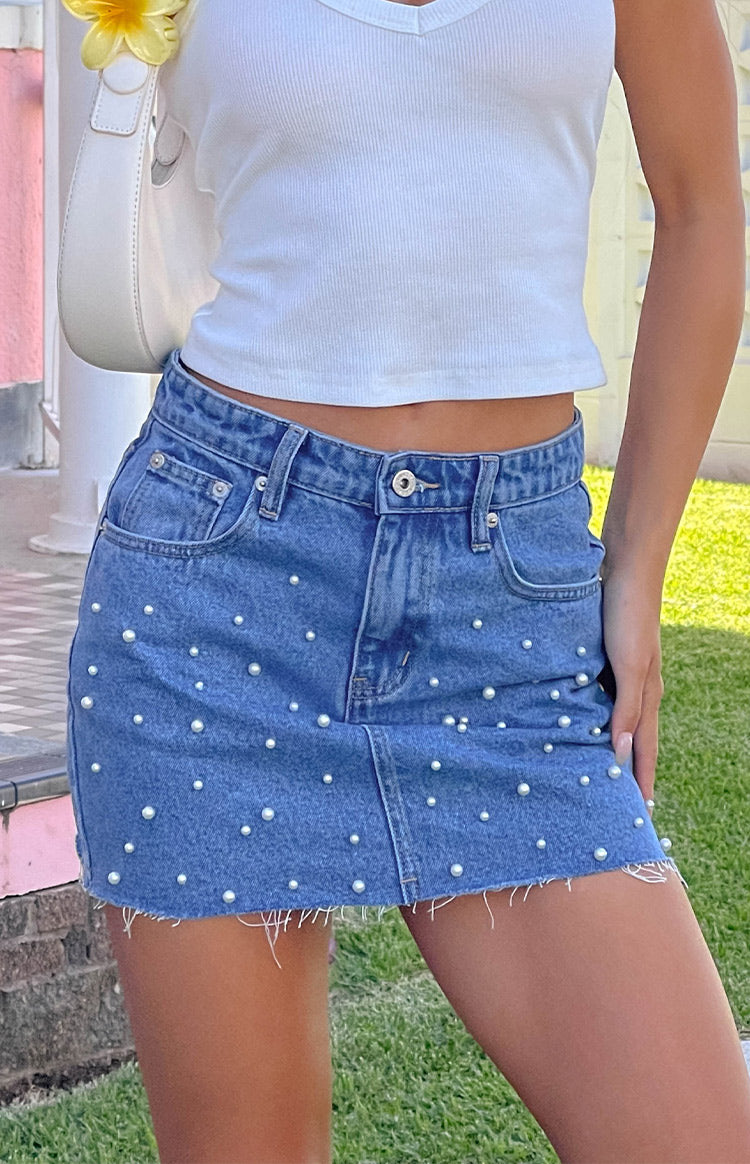 Mid-wash denim mini skirt with scattered pearl embellishments and a raw frayed hem