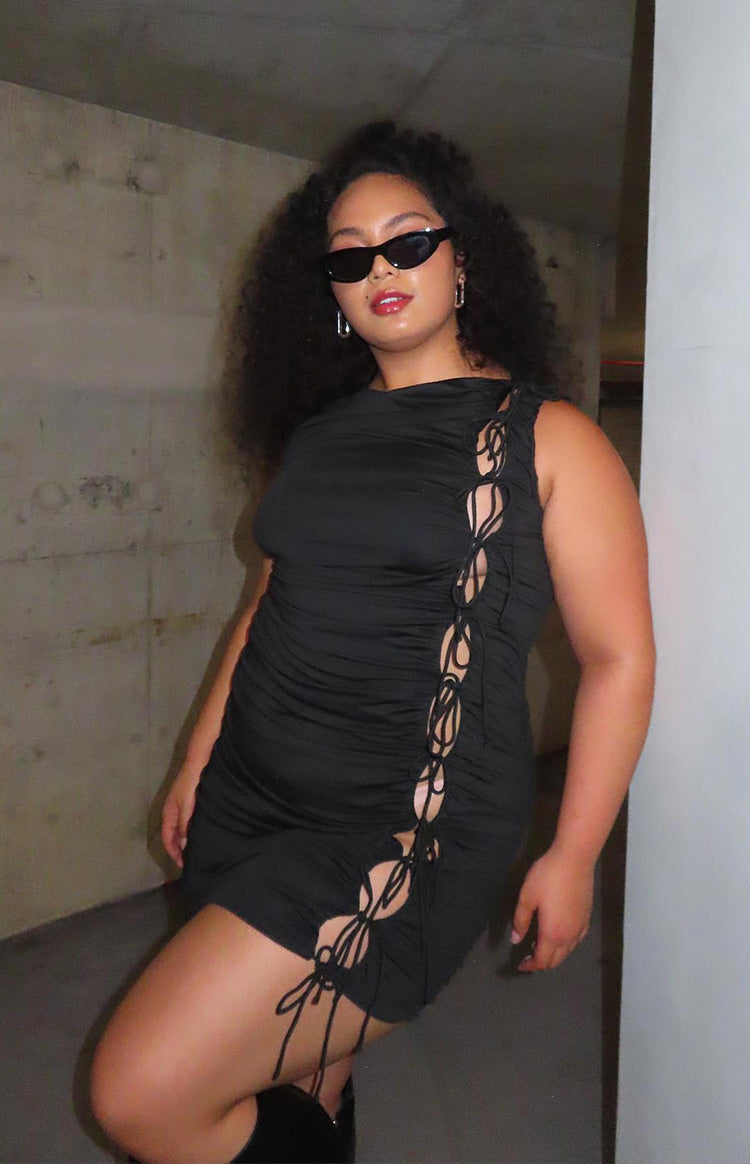 Side view of a black ruched mini dress with a full-length lace-up tie-side detail