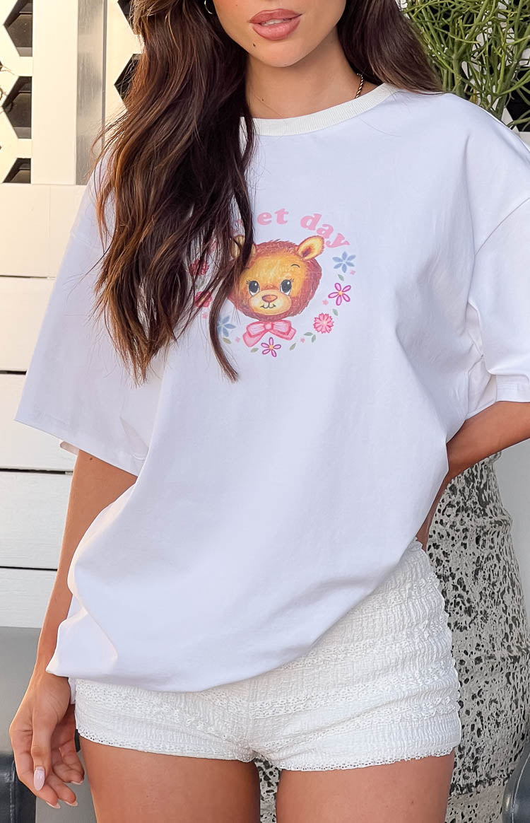 Close-up of the white oversized tee showing the teddy bear graphic print with pink bow and floral wreath
