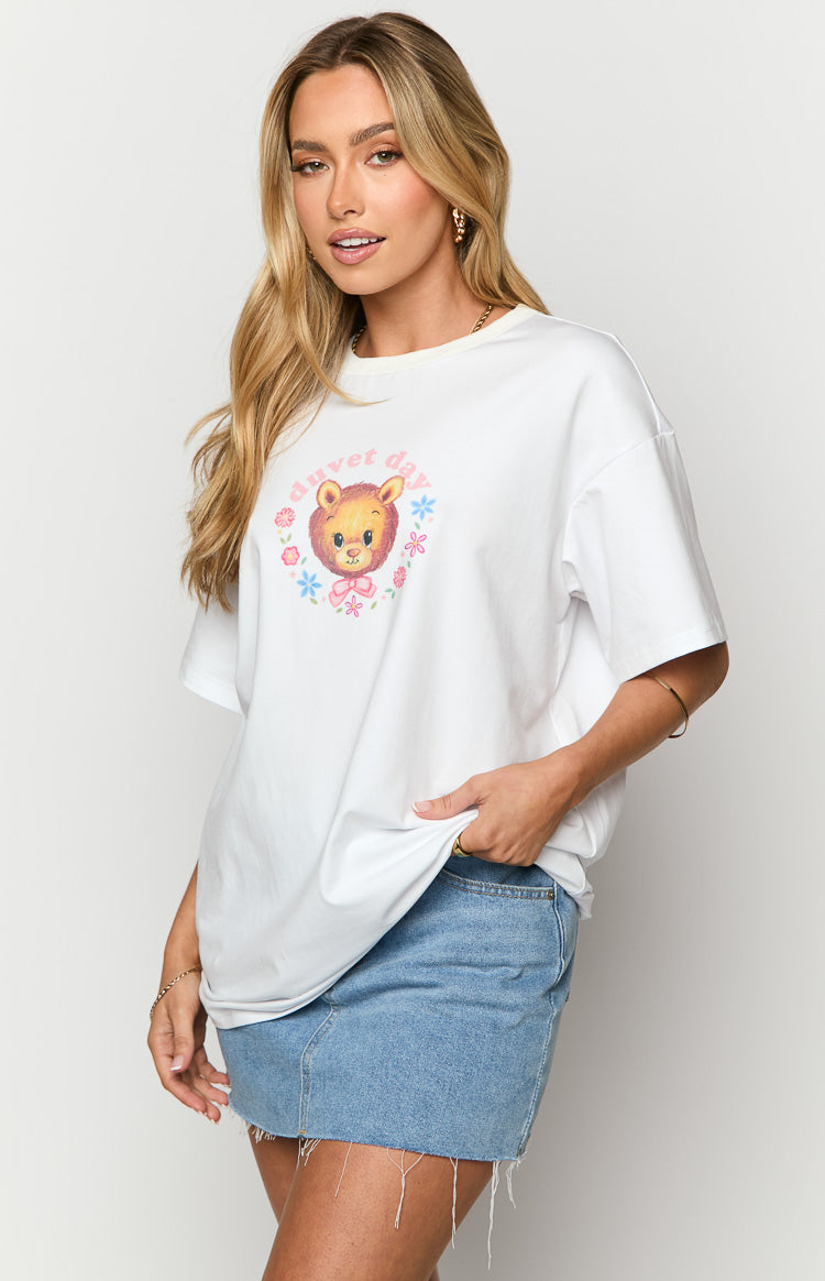 Front view of a white oversized tee with a round neck and a graphic print of a lion cub and 'duvet day' text