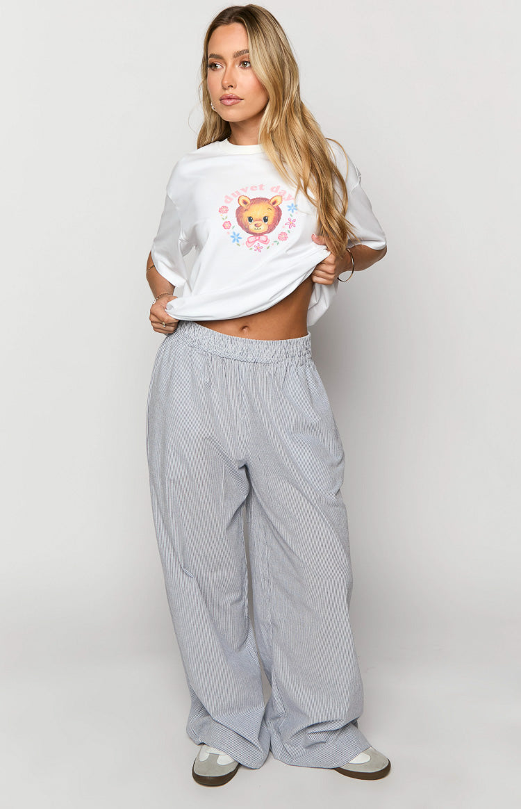White oversized tee with a central graphic of a cartoon bear wearing a pink bow, surrounded by 'duvet day' text and flowers