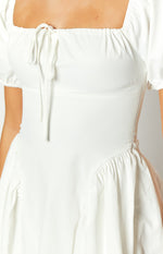 Close-up of the white mini dress showing the square ruched neckline with tie-front detail and fitted bodice