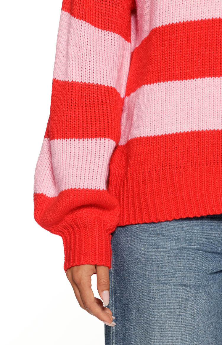 Close-up of the red and pink striped knit sweater sleeve with a balloon shape and thick ribbed cuff