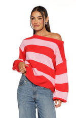 Off-shoulder neckline of a red and pink striped knit sweater with a relaxed fit