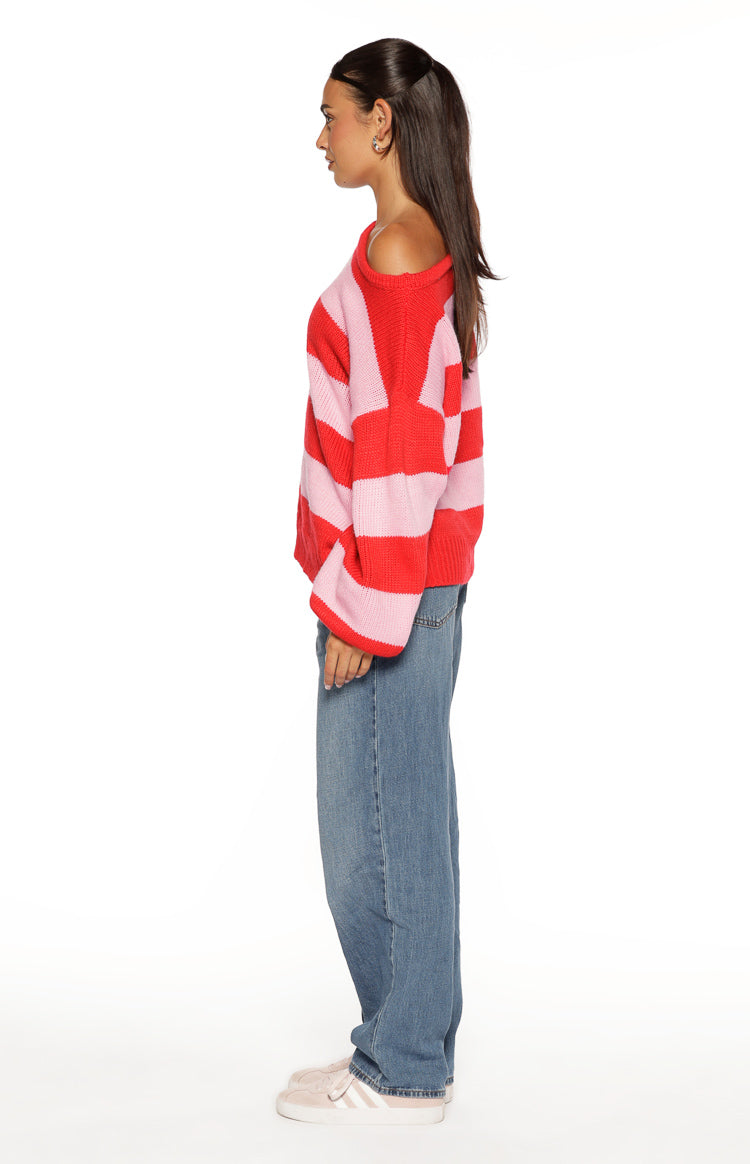 Side view of the red and pink striped off-shoulder knit sweater with a relaxed fit and wide sleeves