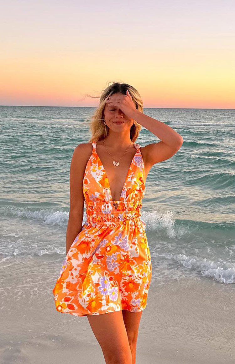 Rear view of an orange floral mini dress with a low open back and thin horizontal strap details