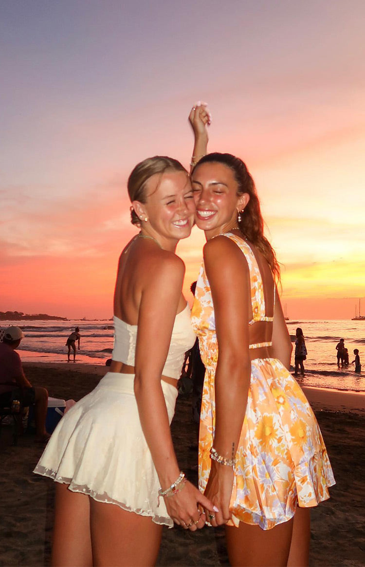Rear view of an orange floral mini dress with a cut-out back, thin straps, and a flowy mini skirt