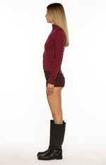 Front view of a burgundy knit sweater with a subtle star pattern, full silver zip, ribbed mock neck, and cropped hem