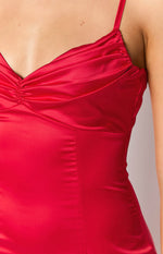 Close-up of the red satin maxi dress showing the ruched V-neck bust, thin spaghetti strap, and bodice seaming