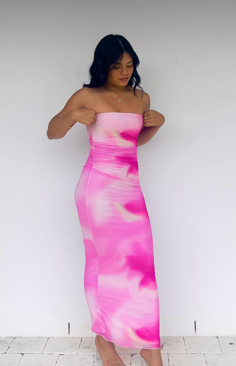Side view of a pink and white tie-dye print strapless maxi dress with ruched detailing on the side and a bodycon fit
